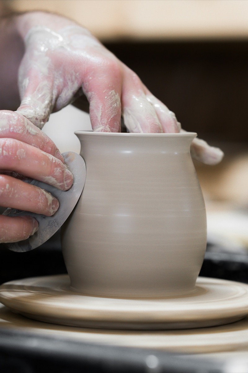 Hands shaping a clay vase on a pottery wheel
