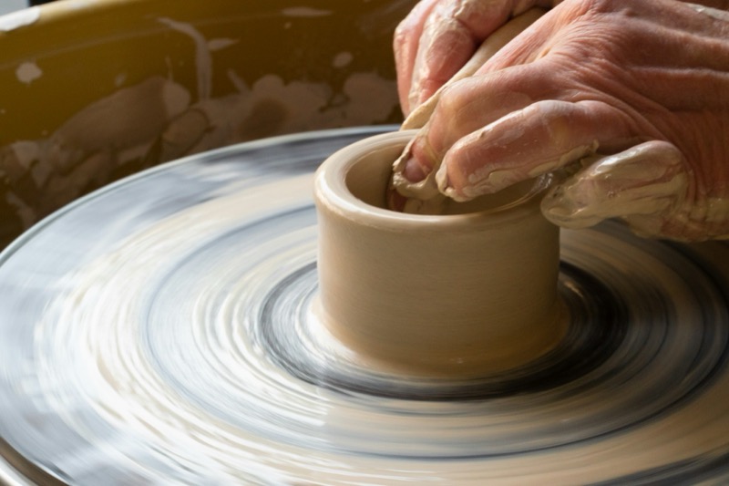 Hands centering clay on a spinning wheel
